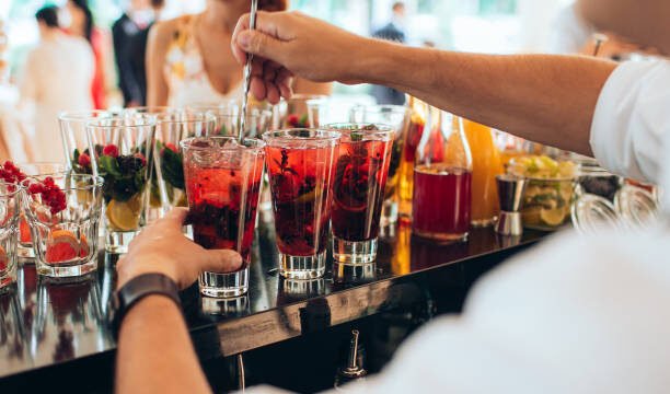 Hand making red cocktail at the open-air wedding party.